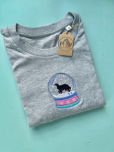 Load image into Gallery viewer, Folded gray t-shirt with a snow globe design and a dog on a light blue background
