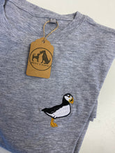 Load image into Gallery viewer, A gray organic cotton t-shirt with a embroidered puffin design on the chest, accompanied by a product swing tag