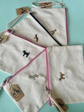 Load image into Gallery viewer, White pouches with embroidered dog designs on a light blue background

