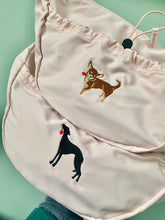 Load image into Gallery viewer, Cross body bags in pink with embroidered dog illustrations in full colour on a green background. one a chihuahua and one black sighthound with red roses in their mouths
